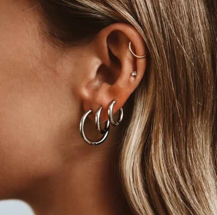 Close-up of an ear wearing multiple hoop earrings with a blurred background